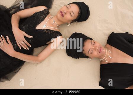 Two woman laying on sand shot from high angle Stock Photo