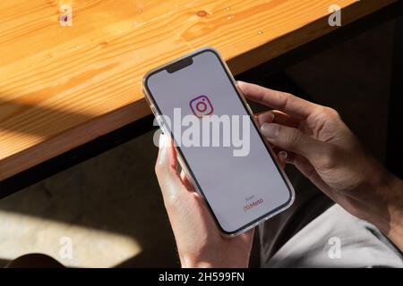 CHIANG MAI, THAILAND - NOV 7, 2021: Man hand holding Iphone 13 with Instagram application on the screen by metaverse, top view. Stock Photo
