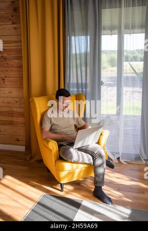 Comfortable place for working at home. A man is working in a big yellow armchair Stock Photo