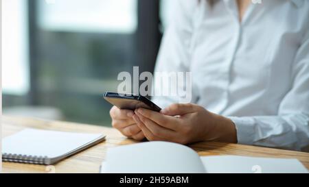 Close-up, Female assistant using smartphone, reading and answering the business email. Stock Photo