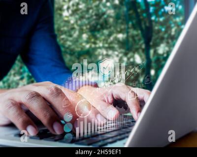 Virtual icon, safety shield, fingerprint, chart, graph from laptop while businessman's hand working, using keyboard computer. Cyber security data prot Stock Photo