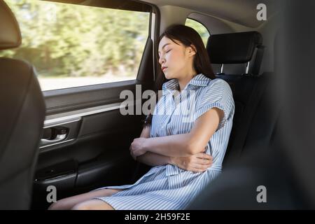 young woman sleeping while sitting in the back seat of car