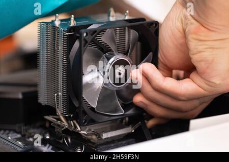 Close up of male hand installing cooler on computer processor. PC assembly and modernization. Person collecting professional PC for cryptocurrency min Stock Photo