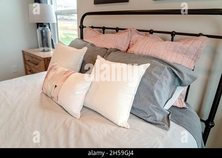 Fluffy pillows on bed with black metal frame inside the cozy bedroom of home Stock Photo