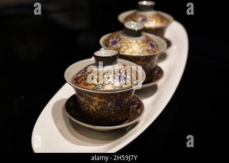 Golden floral pattern oriental tea set with cup, coaster and lit made from ceramic and brightly painted china ware. Stock Photo