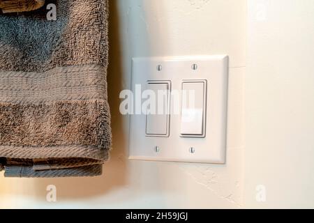 Light switch and hanging gray towel inside the bathroom of a home Stock Photo