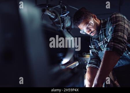 Close up of young concentrated african american industrial man working on cutter in metal workshop. Stock Photo