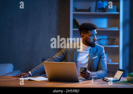 Young african american businessman working indoors in office at night. Stock Photo