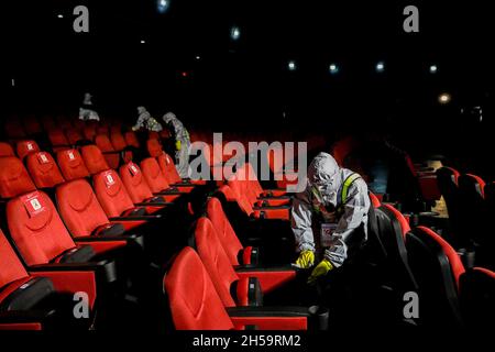 Workers wearing a protective kit sprays disinfectant to sanitize a movie theater as malls prepare to reopen at Robinsons Galleria mall in Quezon City, Metro Manila, Philippines. Stock Photo