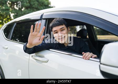 happy man open window of a car and raising his hand Stock Photo