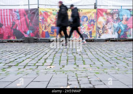 Cologne, Germany. 08th Nov, 2021. Pedestrians walk past barrier grids during set-up work for the carnival kick-off under Corona conditions on 11.11. on Heumarkt. Thursday is traditionally the start of the fifth season in the carnival strongholds. Credit: Federico Gambarini/dpa/Alamy Live News Stock Photo