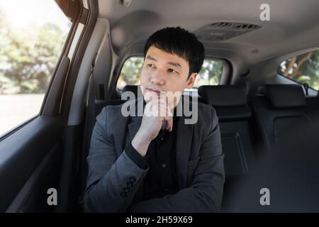young business man thinking while sitting in the back seat of car Stock Photo