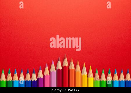 Creative background made of colour pencils on red paper. Flat lay. Education concept. Stock Photo