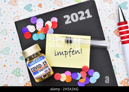 FOTOMONTAGE, Kalender mit Zettel, Spritze, Impfstoff und Aufschrift impfen