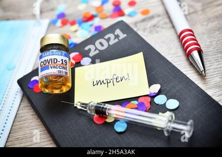 FOTOMONTAGE, Kalender mit Zettel, Spritze, Impfstoff und Aufschrift impfen