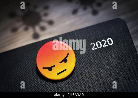 FOTOMONTAGE, Wütender Smiley auf Kalender des Jahres 2020 und Schatten von Coronaviren, Corona-Jahr Stock Photo