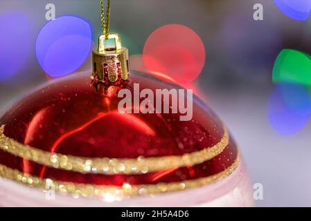 Red colored christmas ball in front of christmas tree's lights, close up, holiday concept, macro photography Stock Photo
