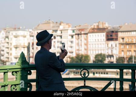Man in a hat taking picture of Budapest old city from the bridge Stock Photo