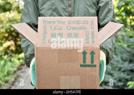 Parcel with text thank you in different languages.  Delivery man is holding a parcel with thank you text in different languages. Stock Photo