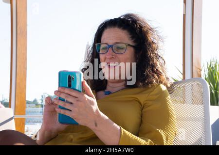Caucasian woman sitting on a terrace talking on a video call with a friend. Stock Photo