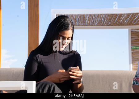 Latin woman sitting on a terrace talking on a video call with a friend. Stock Photo