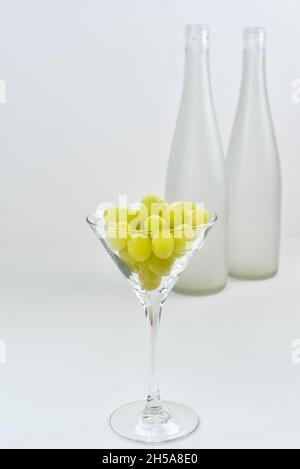 Glass with grapes on the background of a blurry empty wine bottles. Wine production and wine making theme Stock Photo