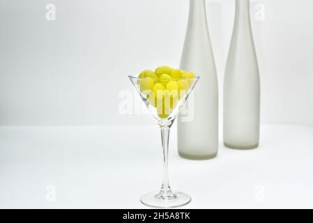 Wine glass with grapes on the background of a blurry empty wine bottles. Wine production and wine making theme Stock Photo