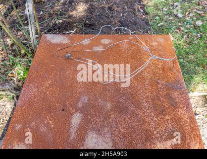 Stockholm, Sweden - April 1, 2021: Artistically formed wire on the rusted metal plate in the garden Stock Photo