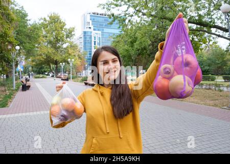 The woman keeps vegetables and fruits in a plastic bag and a cloth shopper. Stock Photo
