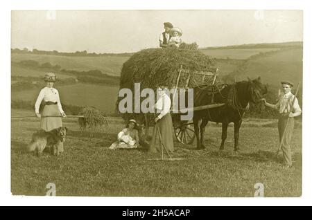 Original early 1900's Edwardian farm greetings postcard of people in a field wearing Sunday Best clothes, bringing in hay, horse and wagon, circa 1901, U.K. Stock Photo