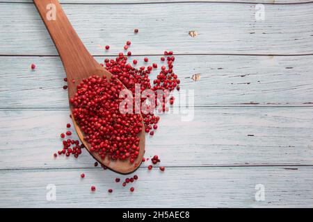 Pink pepper: Names of aroeira-red, aroeira-pementeira or rose-poivre of the species Schinus terebinthifolia, (Anacardiaceae). In a spoon. Top view . Stock Photo