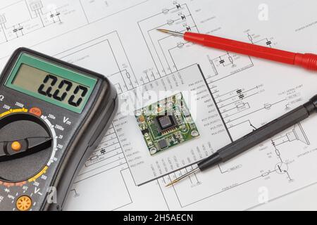 The module with an image sensor and a multimeter lies in the circuit diagram. The concept of debugging, repairing electronic equipment Stock Photo