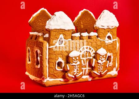 gingerbread house with icing decor on red background. Concept of winter traditional dessert - side view Stock Photo