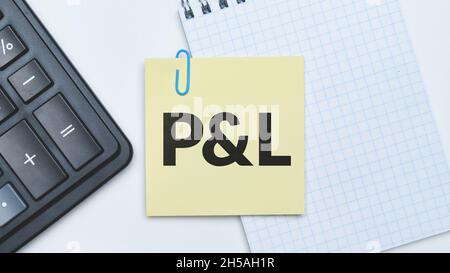 Business acronym Profit and Loss. The inscription on the sticker next to the calculator and notebook. Stock Photo