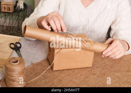 Woman packaging box. Happy holiday present, surprise. Gifts for boxing day. Delivery service, shipping. Focus on hands Stock Photo