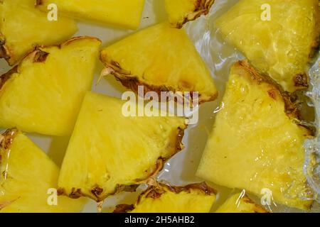 Slices of pineapple in water on white background. Pineapple close-up in liquid with bubbles. Slices of ripe pineapple in water. Macro image of fruits Stock Photo