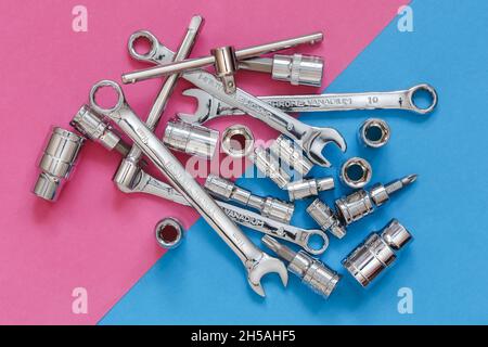 Various wrenches and tools on pink and blue diagonal background, top view Stock Photo