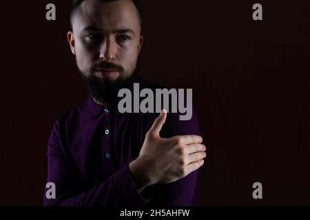 Portrait photo shot of bearded handsome brunet serious confident brutal man in a pensive mood looking away against black background Stock Photo