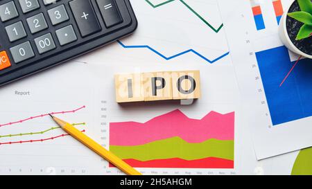 Business acronym IPO or Initial Public Offering. Wooden cubes on financial documents and reports with a calculator Stock Photo