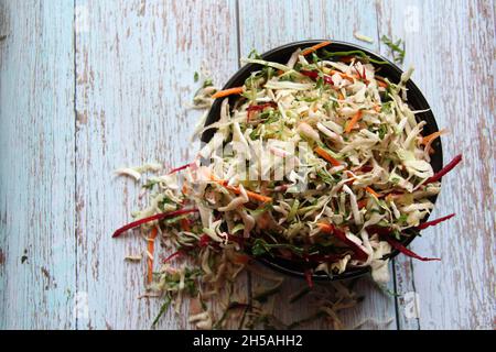 Vegetables and vegetables: carrots, beets and cabbage, grated, close-up, in a black crockery bowl on an old wooden table. View from above. Space for t Stock Photo
