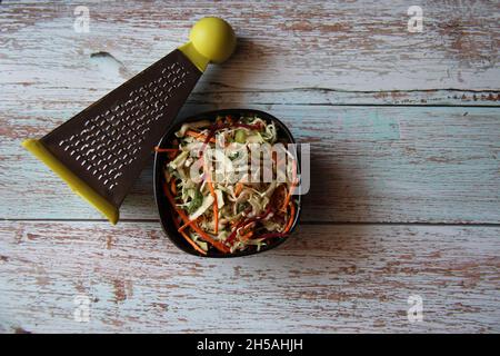 Vegetables and vegetables: carrots, cabbage, beets, grated, in a bowl with a grater on an old wooden table. View from above. Space for text. Stock Photo