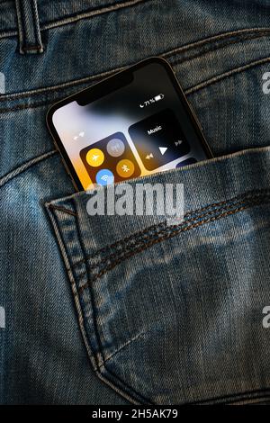 Rear view of denim jeans rear pocket with new Apple Computers Smartphone featuring OLED retina screen with phone control center switched to airpane Stock Photo
