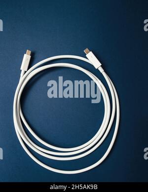 View from above of long USB-C Cable manufactured for fast data and peripheral transmission - isolated on blue background Stock Photo