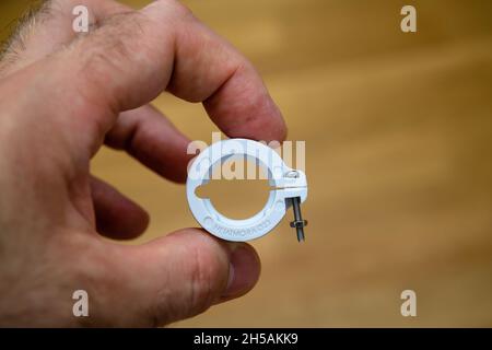 POV male hand holding adapter ring for the Netatmo RA 23 diameter radiator thermostatic valve Stock Photo