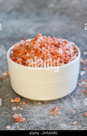 Pink Himalayan rock coarse salt in a white bowl on gray background Stock Photo