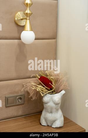 Modern stone vase female silhouette with dried flowers on the bedside table in the bedroom. Soft selective focus, art noise Stock Photo