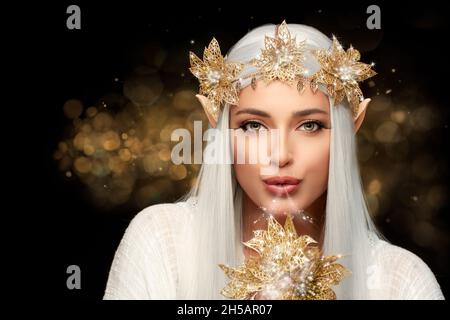 Elf queen with golden flowers wreath looking at camera blowing magic ...