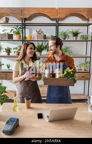 Florists smiling at each other while working with notebook and plants in flower shop Stock Photo
