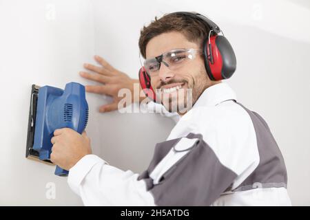professional construction worker using sander on interior wall Stock Photo