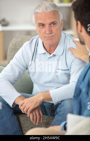 portrait of sad senior man being comforted by his son Stock Photo
